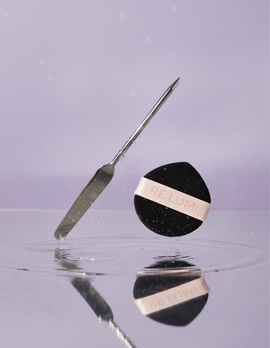 RE LUMI stainless steel spatula and black eco puff over water, highlighting purity, freshness, and sustainable K-beauty design.