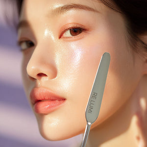 Woman holding RE LUMI stainless steel spatula, showing a radiant, steel-smooth finish and premium K-beauty glow.
